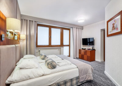 Sypialnia w apartamencie Mezzanine z wielkim oknem i łożem oraz TV